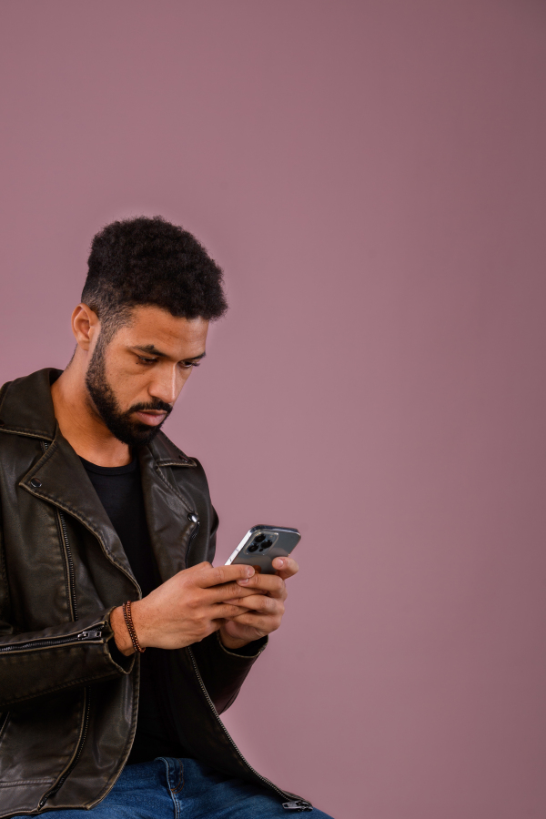 Portrait of young multiracial man with smartphone in a studio.