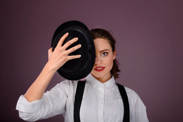 Portrait of a happy young woman in hat, studio shoot.