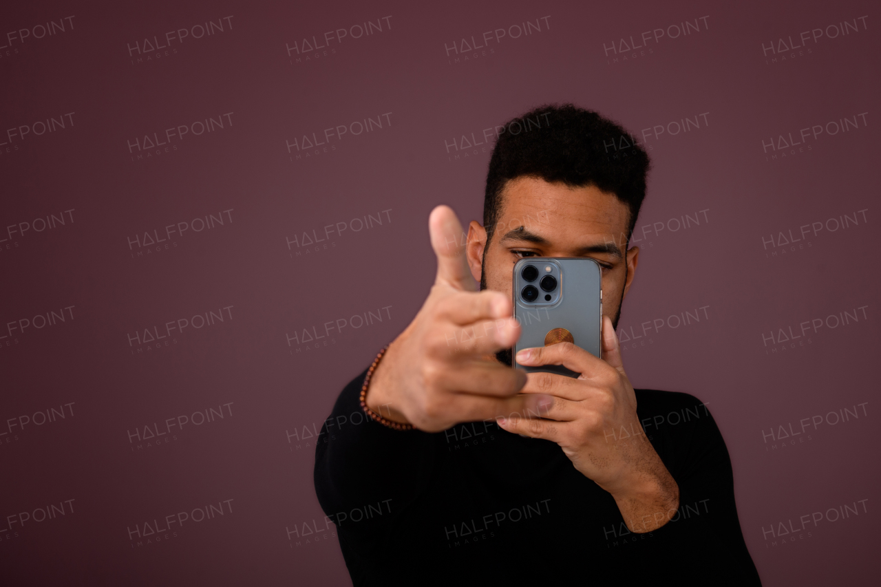 Portrait of young multiracial man with smartphone in a studio.