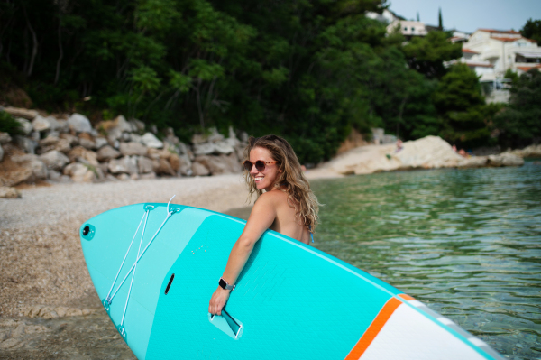 A happy surfer girl walking with board on the sandy beach. Water sports. Healthy Active Lifestyle. Summer Vacation concept.