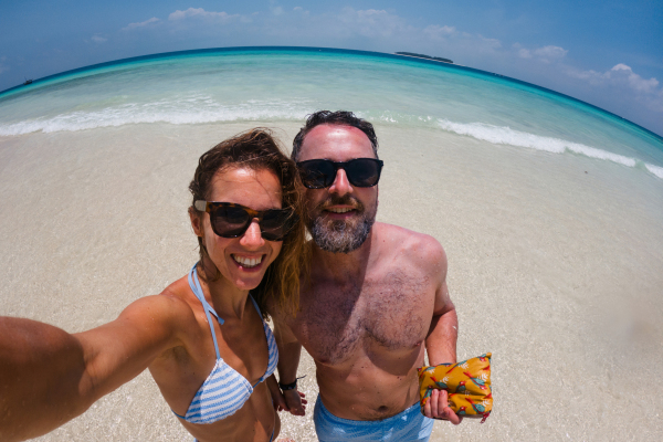 Portrait of beautiful couple on romantic beach vacation. Newlyweds on their honeymoon by the sea on the island of Zanzibar. Fisheye shot with copy space.