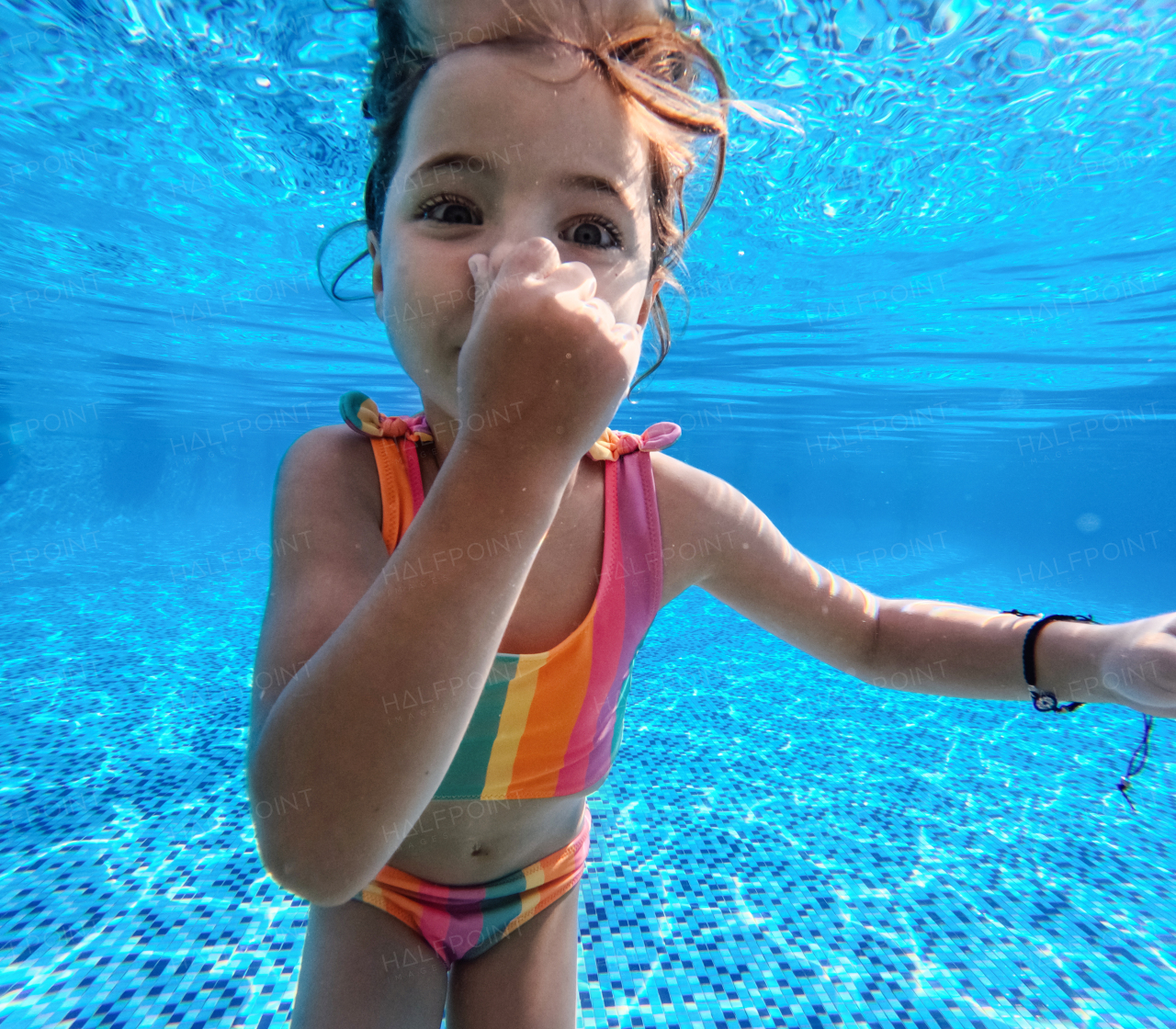 Girl diving underwater in the pool during summer vacation, playing in the water. Beach resort vacation by the sea. Winter or summer seaside holiday. Underwater photography.