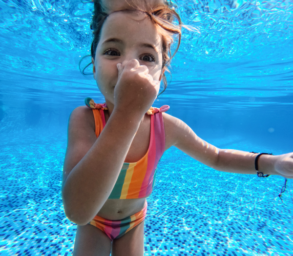 Girl diving underwater in the pool during summer vacation, playing in the water. Beach resort vacation by the sea. Winter or summer seaside holiday. Underwater photography.