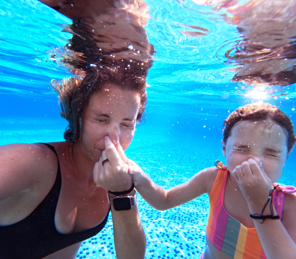 Mother and daughter diving underwater in the pool during summer vacation. Mother and daughter playing in the water. Beach resort vacation by the sea. Winter or summer seaside holiday. Underwater photography.