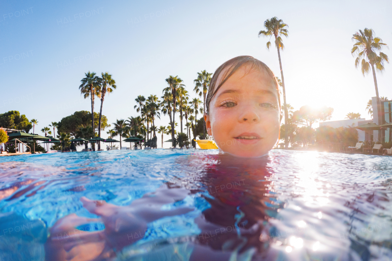 Little girl learning to swim in the pool during summer vacation. Beach resort vacation by the sea. Winter or summer seaside resort holiday.