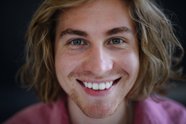 A portrait of confident handsome young man looking at camera on black background, close-up