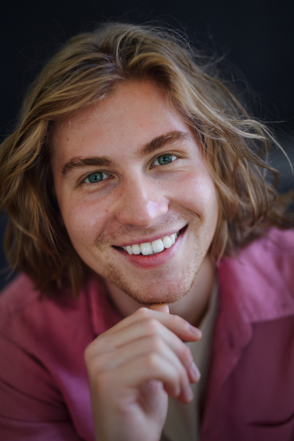 A portrait of confident handsome young man looking at camera on black background, close-up