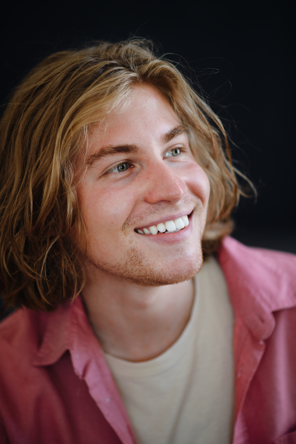 A portrait of confident handsome young man looking away on black background, close-up