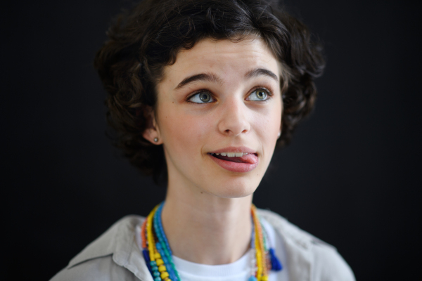 A portrait of funny beautiful teenage girl looking away and daydreaming on black background, close-up