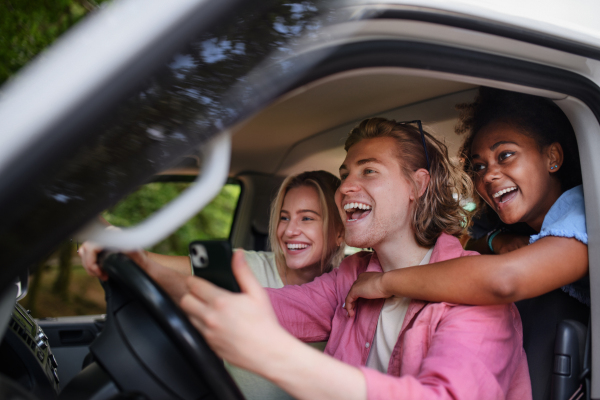 Multiracial young friends travelling together by a car, having fun - summer vacation, holidays, travel, road trip and people concept.