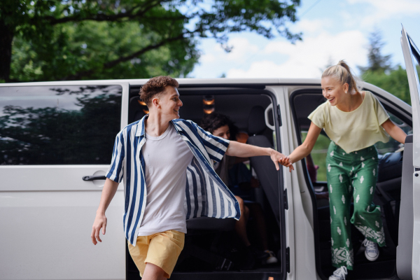 Young friends travelling together by car,getting out from car - summer vacation, holidays, travel, road trip, people concept.