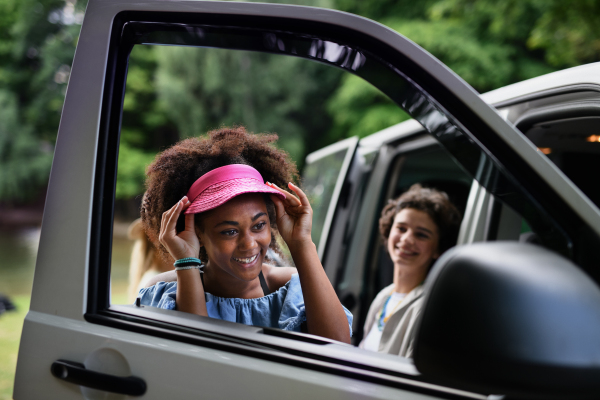 Young multiracial woman looking in a car mirror and checking her visage.