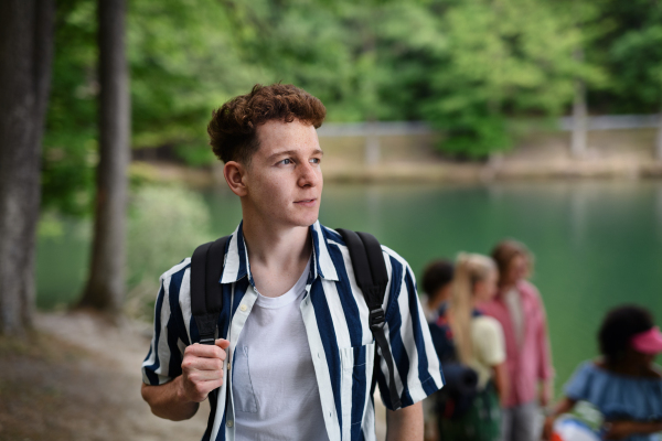 A portrait of young man with friends at background on a hiking or camping trip in the mountains in summer.