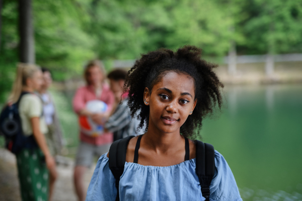 Portrait of young multiracial girl with friends on camping trip at the lake in summer.