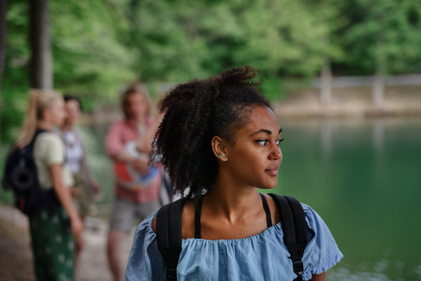 Portrait of young multiracial girl with friends on camping trip at the lake in summer.