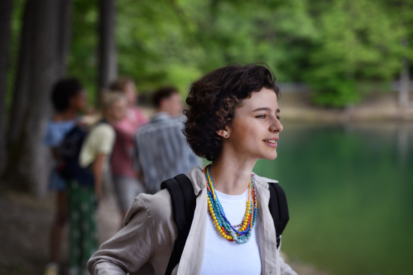 Portrait of young woman with friends on camping trip at the lake in summer.