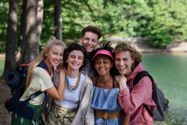 Portrait of group of young friends on camping trip near lake in summer.