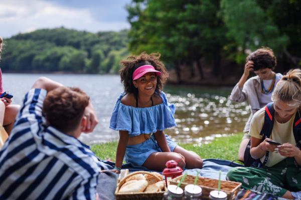 A group of multiracial young friends camping near lake and and having barbecue together.