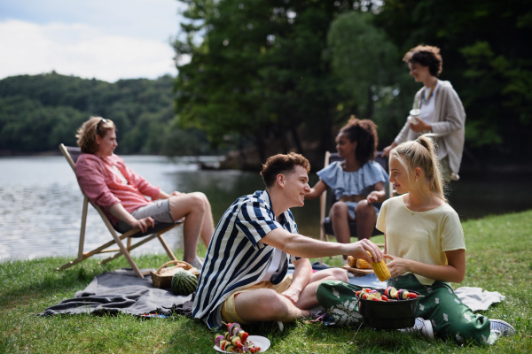 A group of multiracial young friends camping near lake and and having barbecue together.