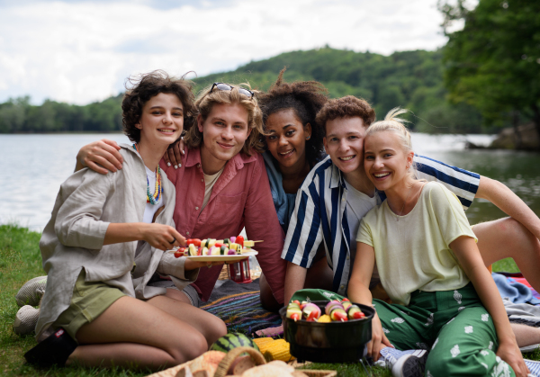 A group of multiracial young friends camping near lake and and having barbecue together.