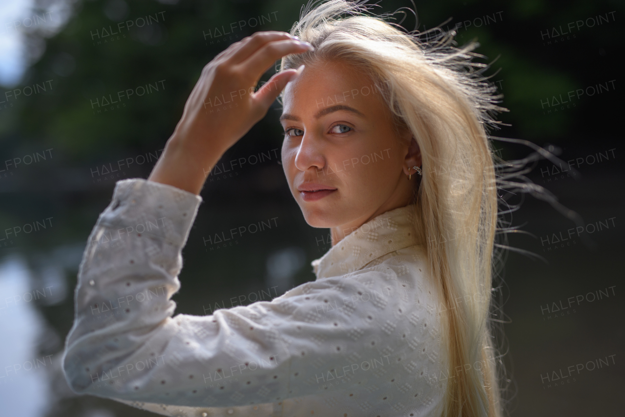 A portrait of beautiful blond young woman looking at camera and smiling, outdoor in the nature.