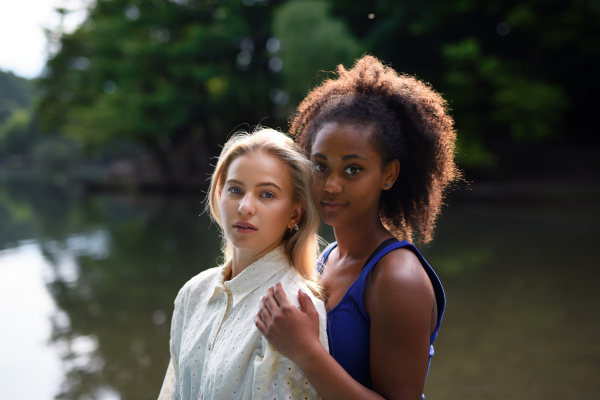 Young women spending time together in the nature, near lake, concept of strong, long lasting friendship.