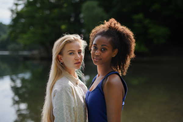 Young women spending time together in the nature, near lake, concept of strong, long lasting friendship.