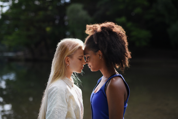 Young women spending time together in the nature, near lake, concept of strong, long lasting friendship.