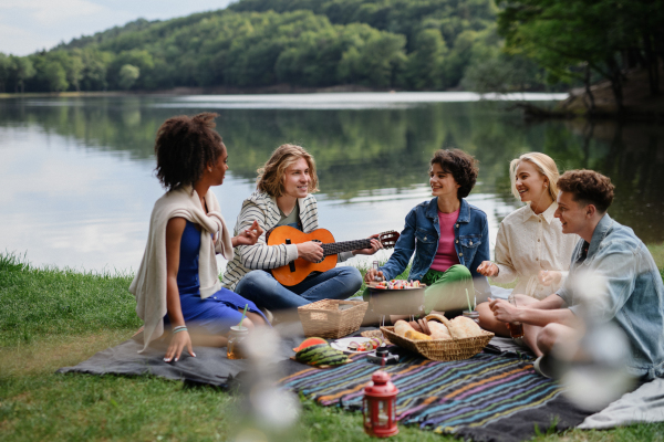 A group of multiracial young friends camping near lake and and having barbecue together.