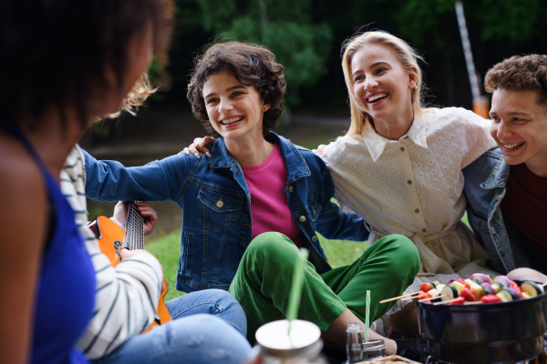 A group of multiracial young friends camping near lake and and having barbecue together. Close-up.