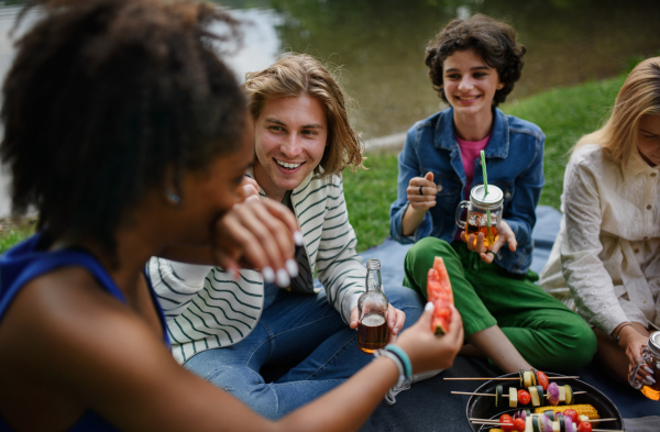 A group of multiracial young friends camping near lake and and having barbecue together.