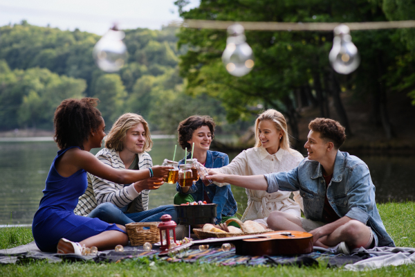 A group of multiracial young friends camping near lake and and having barbecue together.