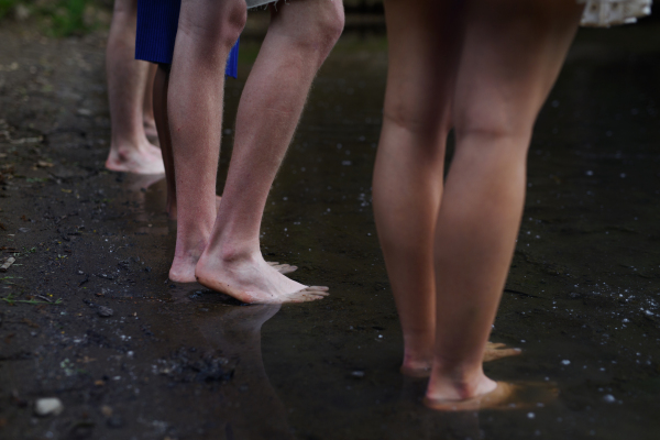 A lowsection of group of friends standing in lake in summer.