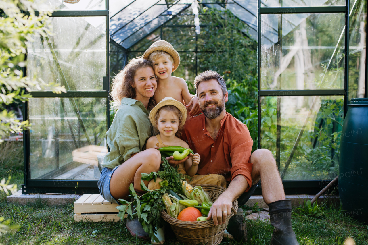 A farmer family with fresh harvest standing in a greenhouse