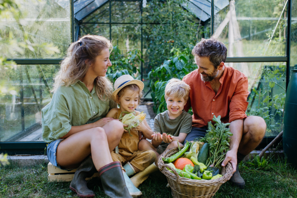 A farmer family with fresh harvest standing in a greenhouse