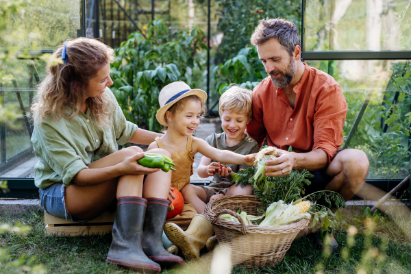 A farmer family with fresh harvest standing in a greenhouse