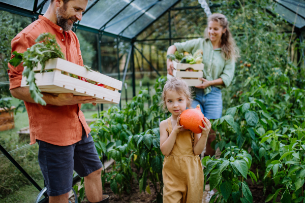 A farmer family with fresh harvest standing in a greenhouse