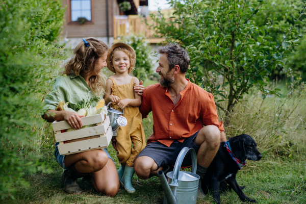 A happy farmer family with fresh harvest together in garden in summer.