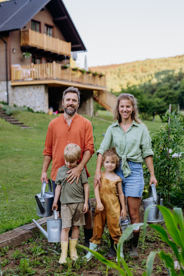 Farmer family watering vegetable garden together in the summer.