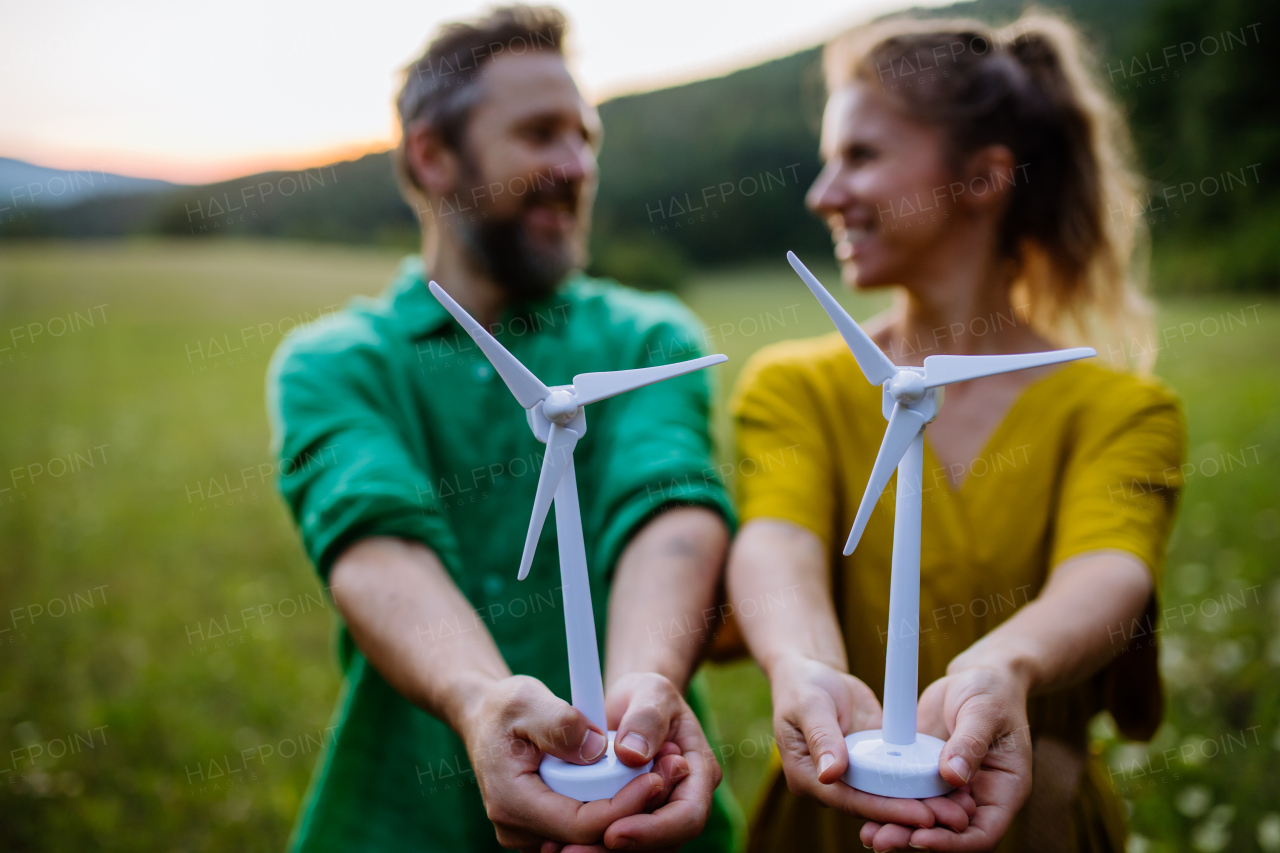 A couple standing in nature with model of wind turbine. Concept of ecology future and renewable resources.