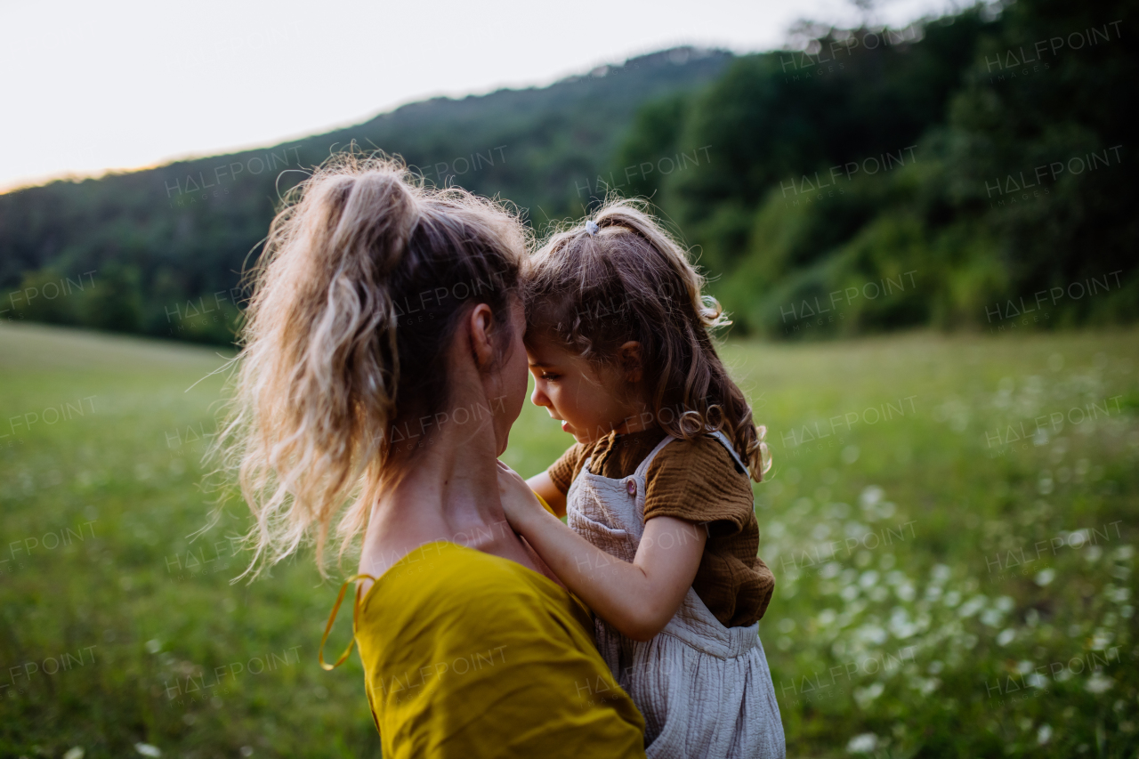 A happy mother spending time with her little daughter outside in green nature.