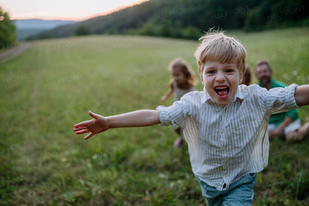 Happy young family spending time together outside in the meadow, little boy running and enjoying nature.