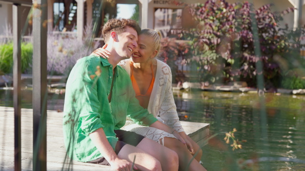 A young couple in love sitting, having legs in natural pool. Enjoying summer time.