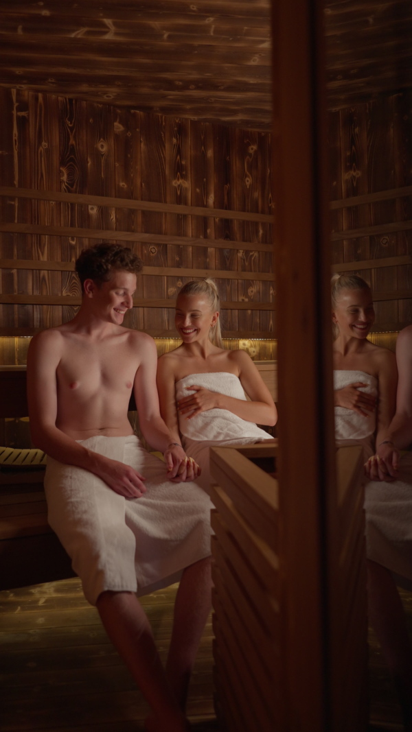 A young couple in love enjoying together time in Finnish sauna, vertical footage.