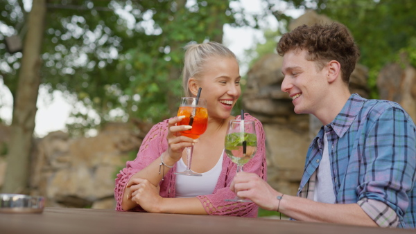 A young couple in love enjoying holiday evening together, sitting, smiling, talking and drinking coktails.