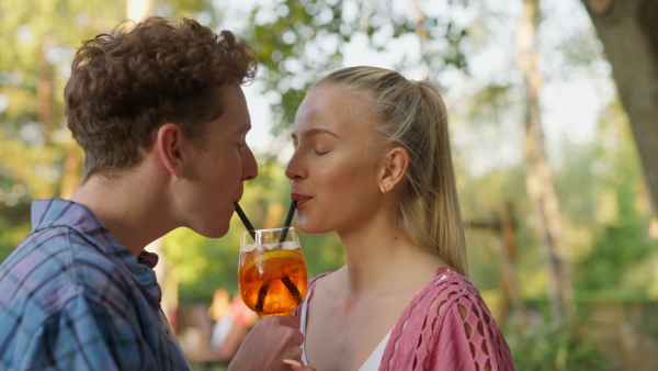 A young couple in love enjoying holiday evening together, sitting, smiling, talking and drinking coktails.