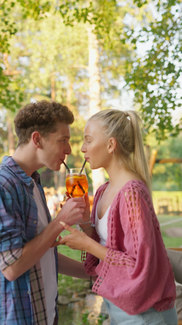 A young couple in love enjoying holiday evening together, sitting, smiling, talking and drinking coktails.