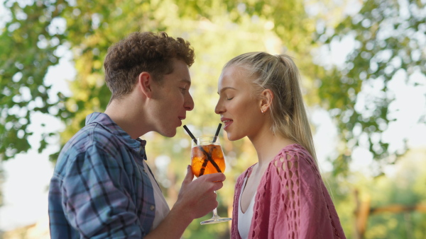 A young couple in love enjoying holiday evening together, sitting, smiling, talking and drinking coktails.