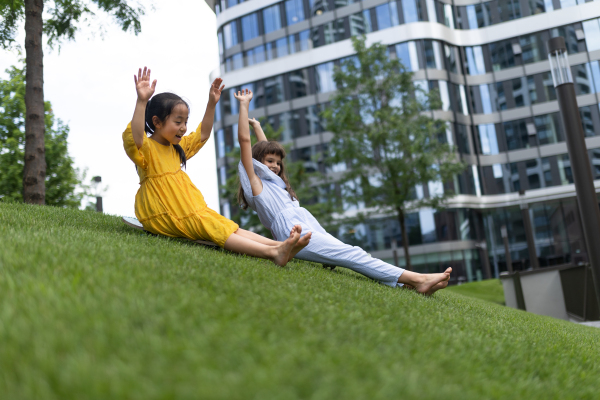 Asian girl trying to skateboarding with her friend in a city park, active kids concept.