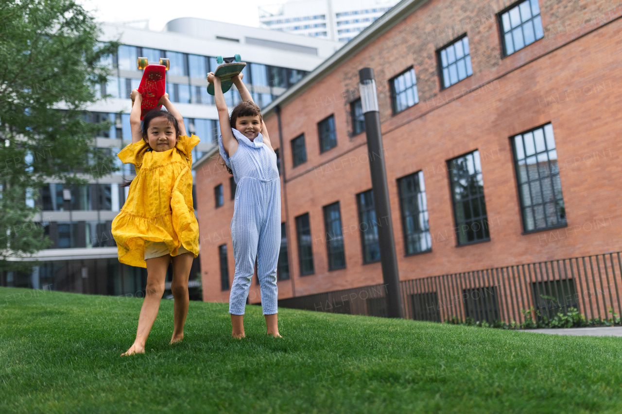 Two girls holding the skateboards over their heads in city park, active kids concept.